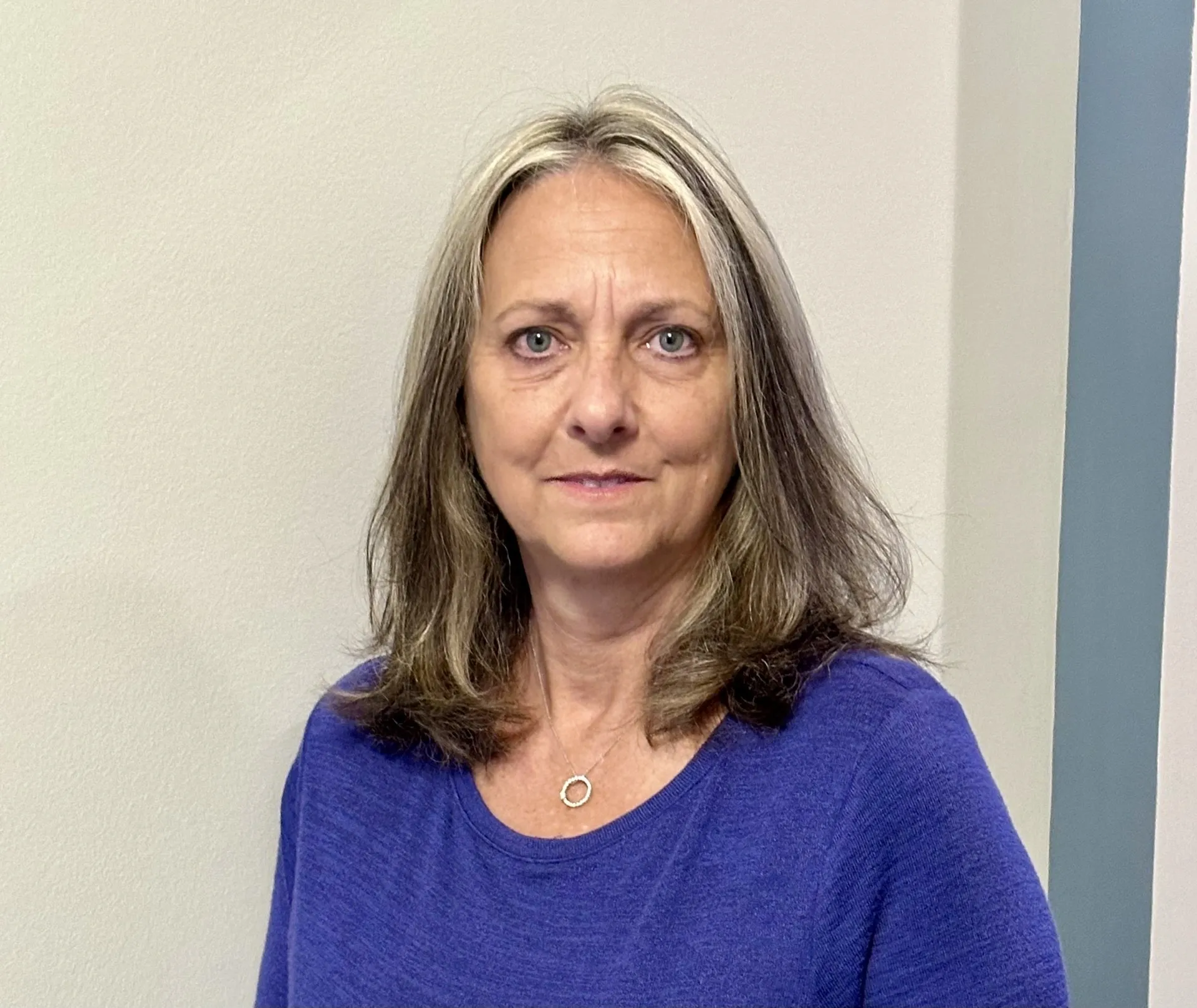 A woman with long hair and wearing a blue shirt.