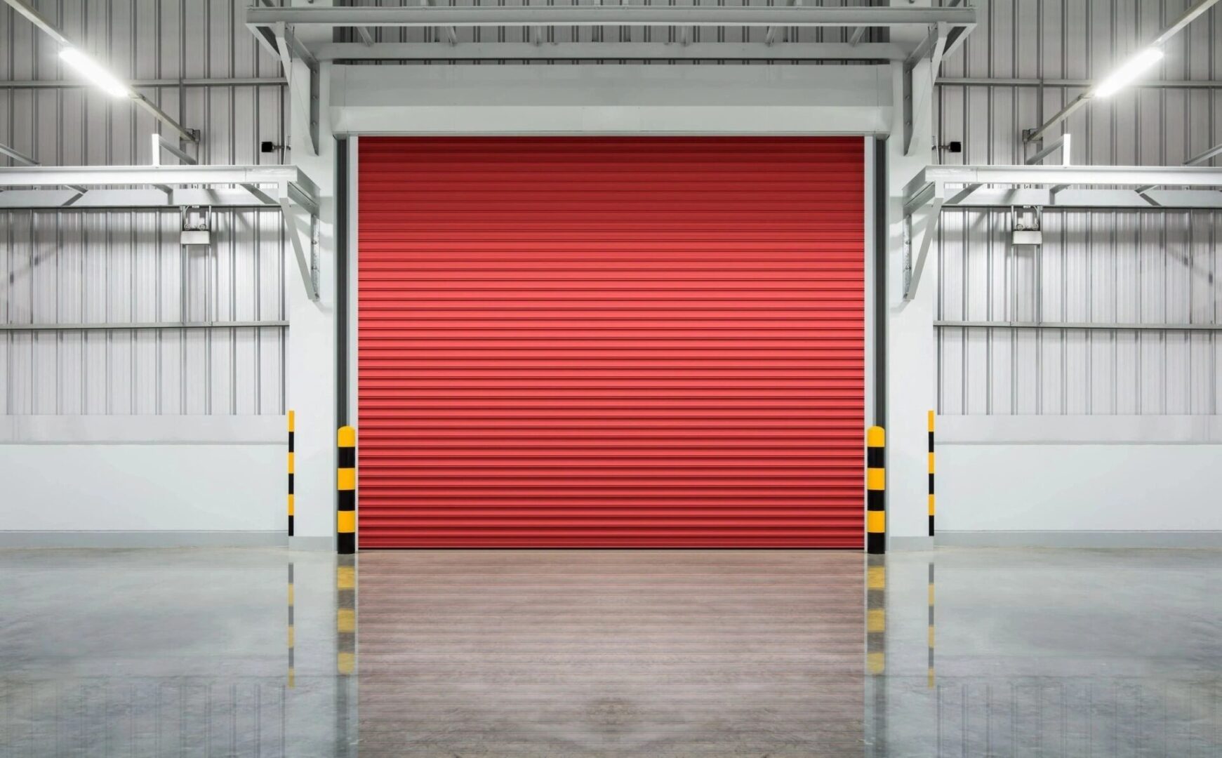 A red garage door in an empty warehouse.