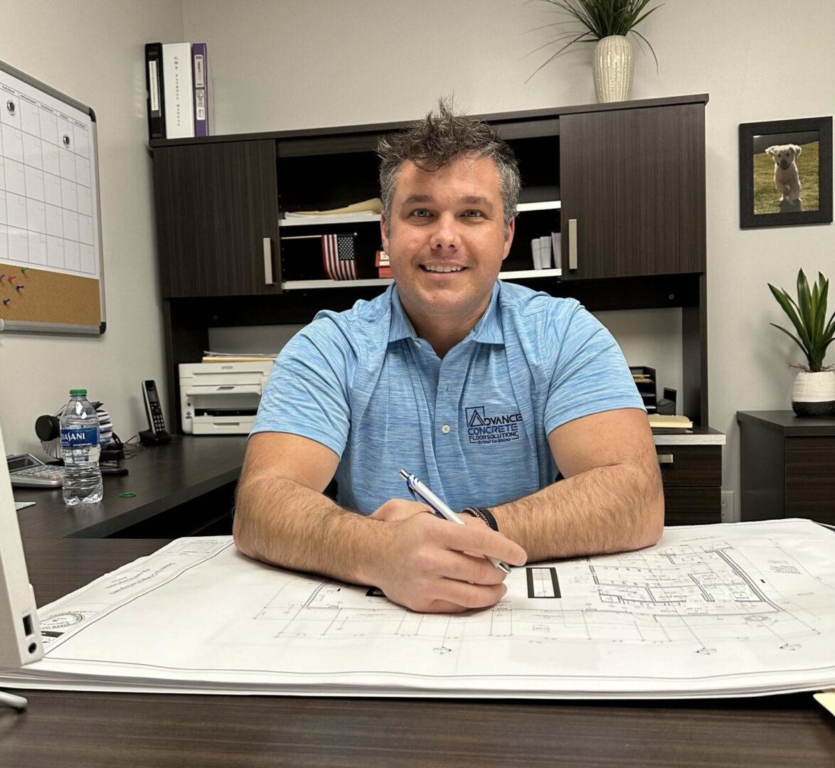 A man sitting at his desk in front of some plans.